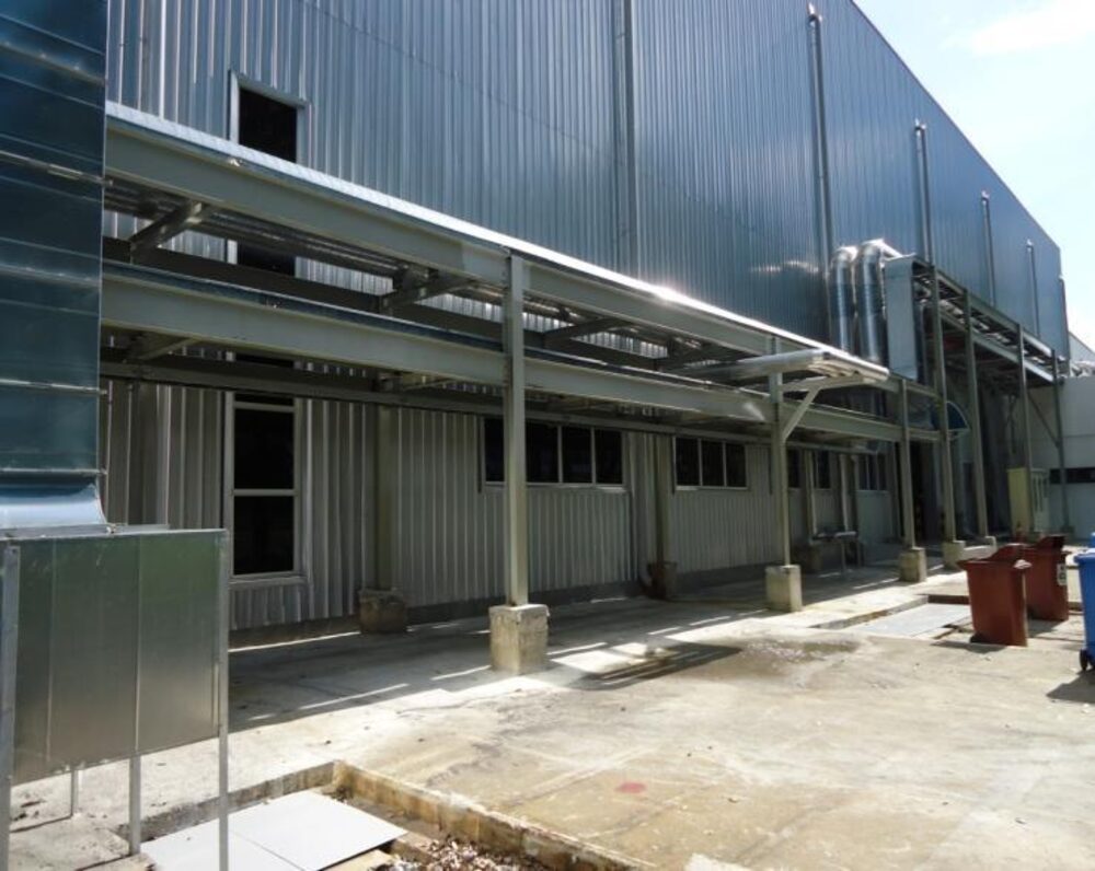 Elevated steel pipe rack alongside an industrial building